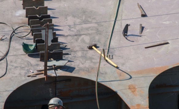 A Design Engineer looks down into a compartment to assess progress